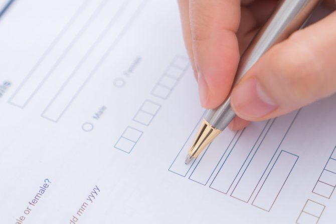 Hand with pen over application form